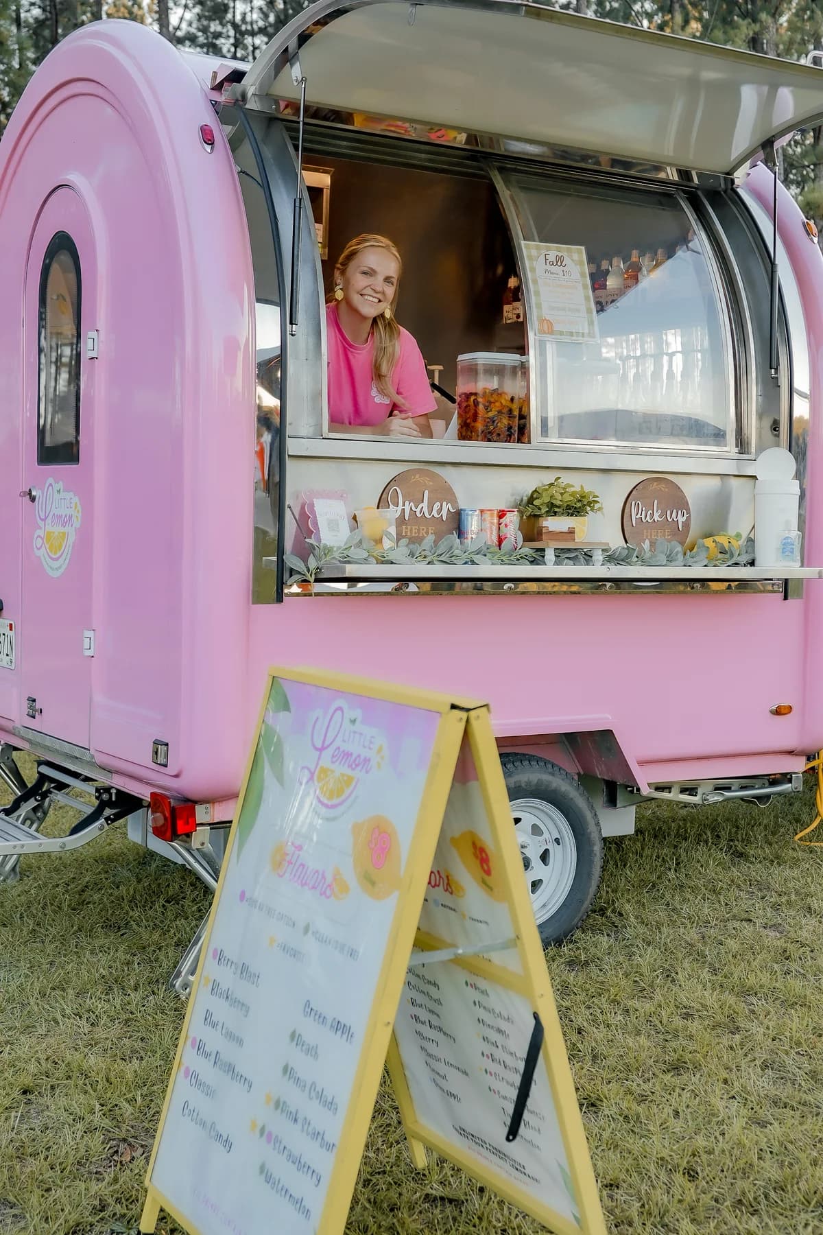Little Lemon Co. owner welcoming customers from the pink trailer’s service window